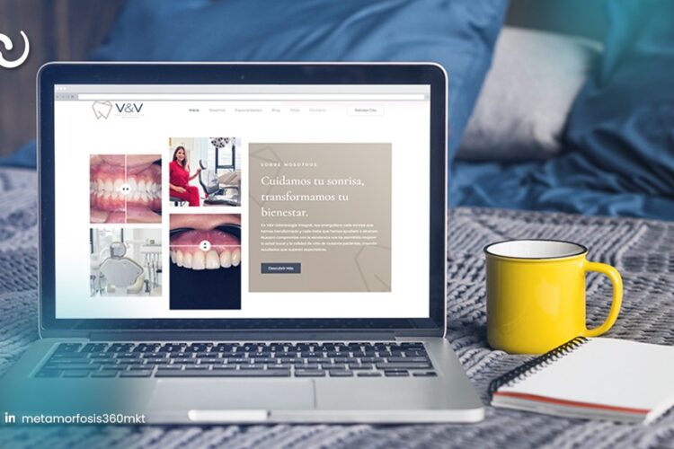 Laptop con la web de la clínica dental V&V, junto a una taza amarilla y un cuaderno