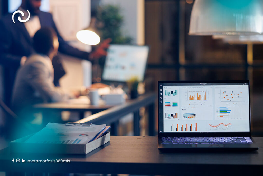 Equipo de marketing y ventas analizando métricas en una laptop con dashboard de resultados y gráficos de rendimiento en oficina corporativa.